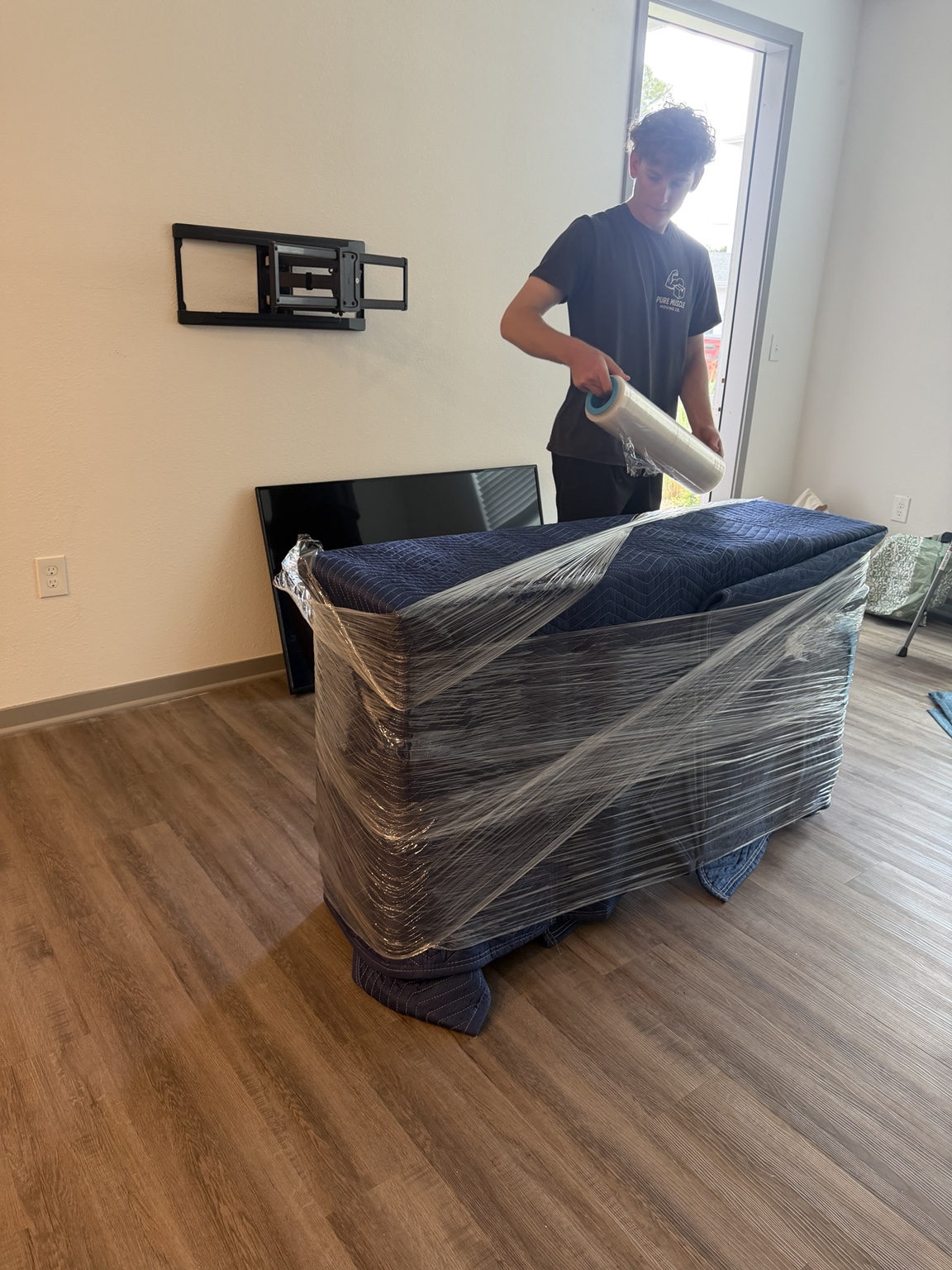 Pure Muscle mover applying stretch wrap over protective moving blankets